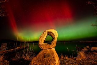 Polarlichter über dem Binnenwasser in Neustadt bilden einen surrealen Hintergrund für die Skulptur „Durchbruch“.