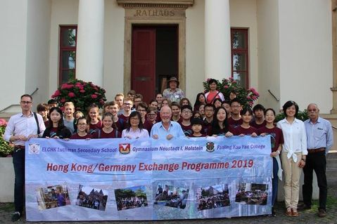 Die beteiligten Schüler und Lehrer aus Hong Kong und Neustadt posieren mit Bürgervorsteher Sönke Sela (Mi.) vorm Rathaus.