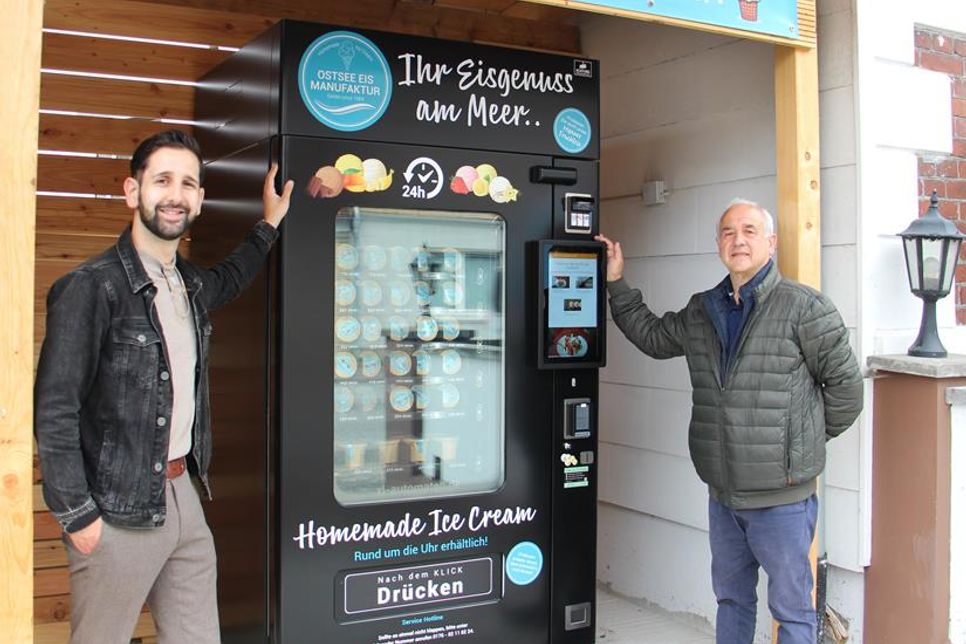 Carlo Ingardia (lks.) und Serafino Ingardia präsentieren den neuen Eisautomaten der „Ostsee Eis Manufaktur“ an der Eutiner Straße 2. Rund um die Uhr bietet der Automat zwölf Sorten Milcheis sowie Sorbets und Spaghettibecher.