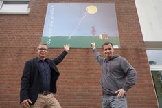 Schulleiter Wolfgang Trosiener (lks.) und Elektromeister Jan Rosenow von Mangels & Mau zeigen die wieder aufgehübschte Holztafel.