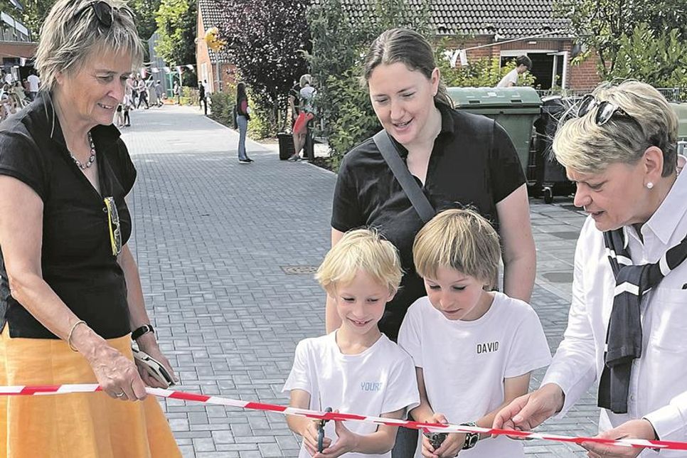 (v.l.) Hilla Mersmann (Bürgermeisterin) Iris Moldenhauer (Vorsitzende des Schulelternbeirats) und Kirsten Sandberg (Schulleiterin) schauen gespannt zu, während die Erstklässler Youri und David ein Absperrband durchschneiden, um den neuen Schulhof offiziell einzuweihen.