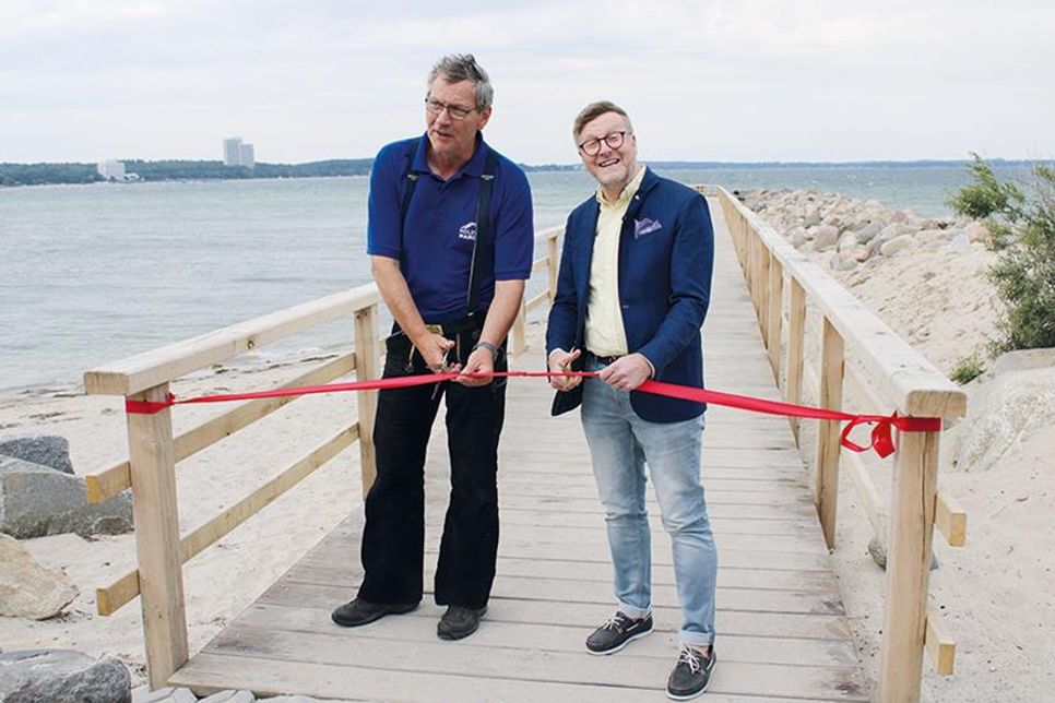 Bürgermeister Sven Partheil-Böhnke und Wolfgang Hargus (links) von der gleichnamigen Holzbaufirma durchschneiden das obligatorische Band und eröffnen damit offiziell den kleinen Molensteg am Niendorfer Freistrand, der an der Hafeneinfahrt wieder neu errichtet wurde.