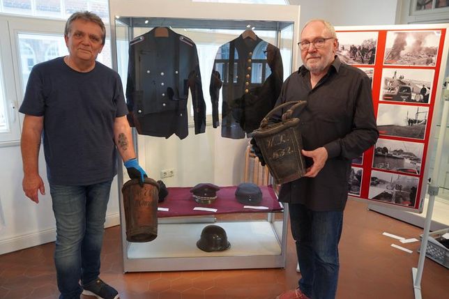 Die Kuratoren Thomas Schwarz (lks.) und Norbert Kahl vor historischen Uniformen (rechts von 1900) mit Löscheimern aus Leder, die nach dem Stadtbrand von 1817 jeder Bürger besitzen musste.