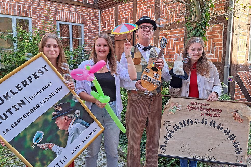 Bänkelsänger Christof Peters und die Auszubildenden der Tourist-Info Eutin, Lara Kuhlmann, Kimberly Schoering und Viktoria Meier (von links), laden zum Gauklerfest ein.