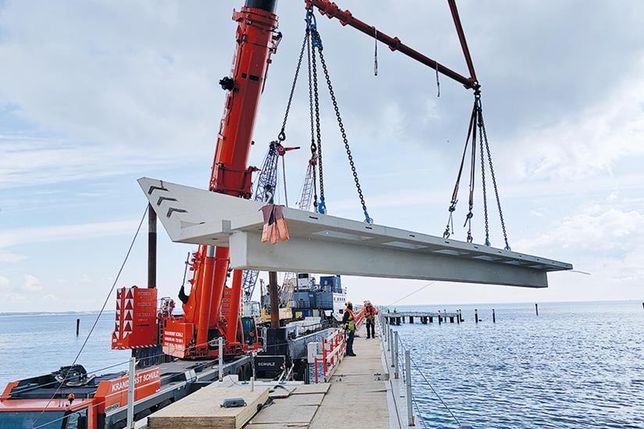 Das erste 45 Tonnen schwere Stahlbetonfertigteil der nördlichen Balkone schwebt über der neuen Scharbeutzer Seebrücke.