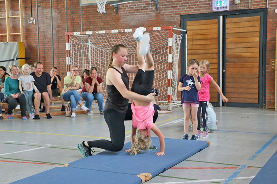 Aus dem Handstand in die Brücke – Lani zeigt diese eher schwierige Übung beim „Vorturnen“ der BSG Eutin mit Hilfestellung von Helferin Hannah. Im Hintergrund beobachten das stolz Mutter Magdalena und Oma Jolanta (auf der Bank).